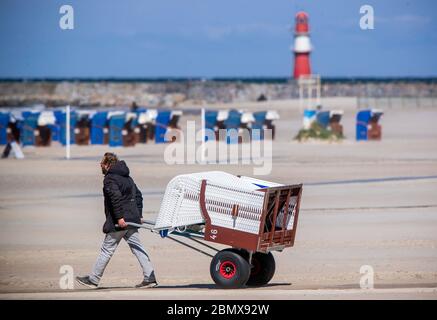 Rostock, Allemagne. 11 mai 2020. Un propriétaire utilise une voiturette pour apporter une chaise de plage en osier à son espace de stationnement à la plage de Warnemünde. Après un renouveau de desserrage de la couronne, les meubles de plage peuvent maintenant être loués à nouveau aux vacanciers et aux baigneurs. Cependant, en raison du temps froid et orageux avec des températures autour de huit degrés, il n'y avait presque pas de visiteurs sur la côte Baltique. Credit: Jens Büttner/dpa-Zentralbild/dpa/Alay Live News Banque D'Images