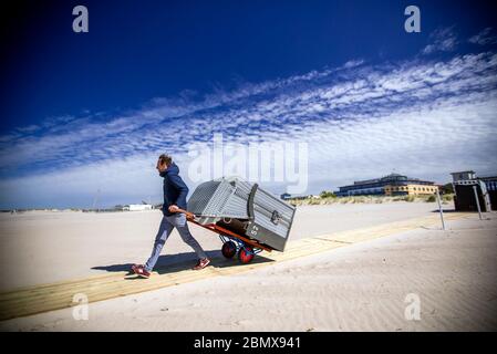 Rostock, Allemagne. 11 mai 2020. Un propriétaire utilise une voiturette pour apporter une chaise de plage en osier à son espace de stationnement à la plage de Warnemünde. Après un renouveau de desserrage de la couronne, les meubles de plage peuvent maintenant être loués à nouveau aux vacanciers et aux baigneurs. Cependant, en raison du temps froid et orageux avec des températures autour de huit degrés, il n'y avait presque pas de visiteurs sur la côte Baltique. Credit: Jens Büttner/dpa-Zentralbild/dpa/Alay Live News Banque D'Images