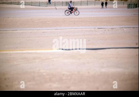 Rostock, Allemagne. 11 mai 2020. Un cycliste est sur la plage presque déserte de Warnemünde. Mais en raison du temps froid et orageux avec des températures autour de huit degrés, il n'y avait presque pas de visiteurs sur la côte Baltique. Credit: Jens Büttner/dpa-Zentralbild/dpa/Alay Live News Banque D'Images