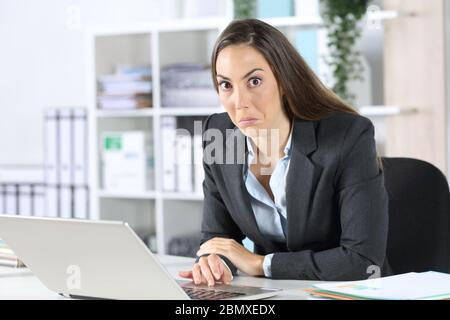 Une femme de direction a confondu un ordinateur portable regardant un appareil photo assis sur son bureau Banque D'Images