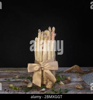 asperges blanches vue latérale sur une table en bois avec fond noir Banque D'Images