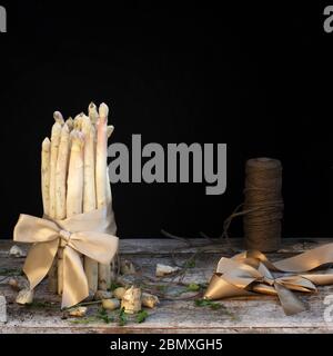 asperges blanches vue latérale sur une table en bois avec fond noir Banque D'Images