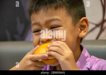 Poisson de hamburger dans la main asie garçon tenant la nourriture. Banque D'Images