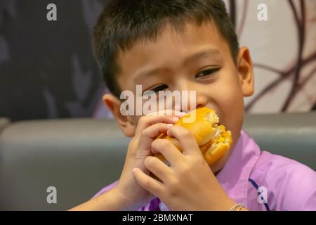 Poisson de hamburger dans la main asie garçon tenant la nourriture. Banque D'Images