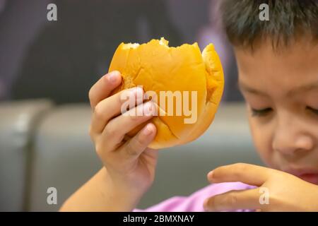 Poisson de hamburger dans la main asie garçon tenant la nourriture. Banque D'Images