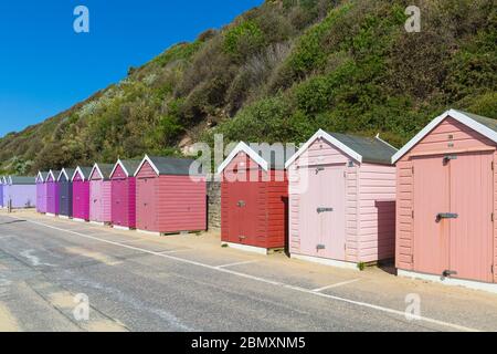 Des cabanes de plage colorées dans une rangée avec le ciel bleu lors d'une chaude journée ensoleillée à Bournemouth, Dorset Royaume-Uni en mai Banque D'Images