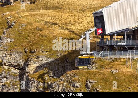 Wengen, Suisse - 10 octobre 2019 : téléphérique jaune arrivant du village de montagne au point de vue sur la falaise de Mannlichen Banque D'Images