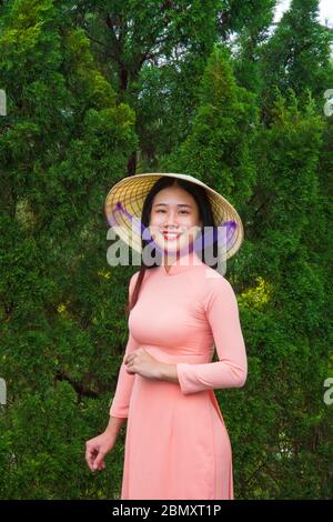 Une femme vietnamienne vêtue d'une robe Ao Dai à la porte d'un temple Banque D'Images