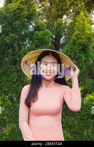 Une femme vietnamienne vêtue d'une robe Ao Dai à la porte d'un temple Banque D'Images