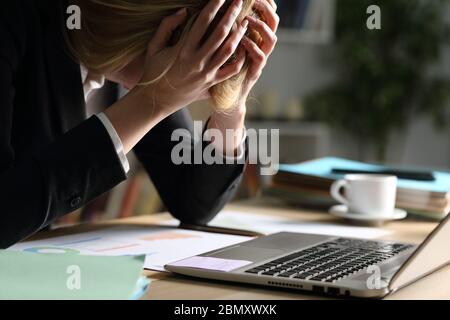 Gros plan de la triste femme d'entrepreneur se plaignant de mauvais résultats la nuit sur un bureau à la maison Banque D'Images