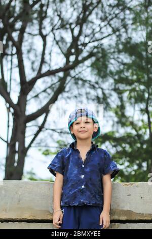 Portrait d'un garçon Asie derrière les arbres. Banque D'Images