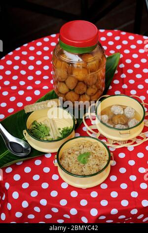 Le savoureux petit déjeuner asiatique consiste en un repas de riz cuit à la vapeur assaisonné avec une soupe de porc aux prunes aigre, prise en studio avec des ingrédients (pot aux prunes) sur une table rouge à pois Banque D'Images