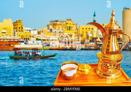 Dégustez un café arabe traditionnel, préparé dans une cafetière dallah, assis sur la rive de la crique de Dubaï et regardant les bateaux abra, flottant de Bur Dubai à Dei Banque D'Images