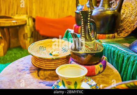 La traditionnelle jebena éthiopienne marmite pour la cérémonie du café se tient sur la table en bois vintage, à côté de la tasse de café et des assiettes tissées pour le pop-corn Banque D'Images