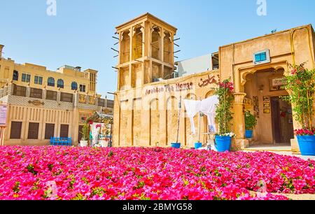 DUBAÏ, Émirats Arabes Unis - 2 MARS 2020 : le lit de fleurs petunia en forme de tapis devant la maison de thé arabe, situé dans un bâtiment d'argile vintage avec un barjeel wincatche Banque D'Images