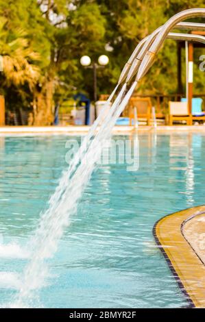 Eau propre qui coule de nombreux cols de cygne dans une piscine avec des gouttes étincelantes Banque D'Images