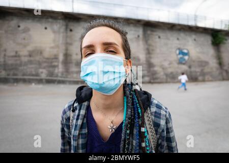 portrait d'une jeune femme rebelle avec une coiffure rasta dans un cadre urbain portant un masque de protection couvrant son visage et laissant voir ses yeux fac Banque D'Images