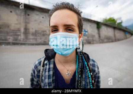 portrait d'une jeune femme rebelle avec une coiffure rasta dans un cadre urbain portant un masque de protection couvrant son visage et laissant voir ses yeux fac Banque D'Images