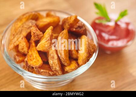 Des quartiers de pommes de terre frits frais et croustillants faits maison dans un bol en verre avec ketchup. Gros plan Banque D'Images