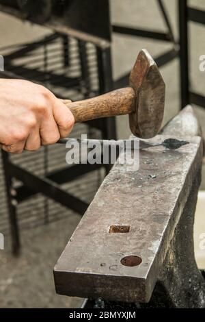 Puyallup, Washington, États-Unis. Forgeron féminin travaillant un motif de feuilles sur un fer chaud. Banque D'Images