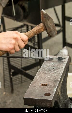 Puyallup, Washington, États-Unis. Forgeron féminin travaillant un motif de feuilles sur un fer chaud. Banque D'Images