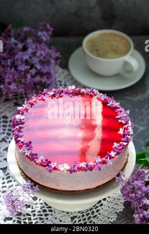 Un gâteau de mousse aux baies à base de chocolat et de jus de gelée, décoré de fleurs de lilas, servi avec du café. Banque D'Images