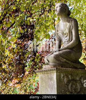 Statue de jeune fille sur pierre tombale avec un écran de feuilles de hêtre en cuivre au cimetière de Brompton, Kensington, Londres. Banque D'Images