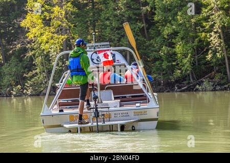 Vue arrière du bateau à réaction « River Safari » de Blue River : le guide se tient à la barre, les passagers en gilets de sauvetage rouges sont assis devant lui, un drapeau canadien flotte à la proue. District régional de Thompson-Nicola, Colombie-Britannique, Canada Banque D'Images