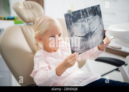Une petite fille avec une radiographie dans une chaise de dentiste. Dentisterie, santé Banque D'Images