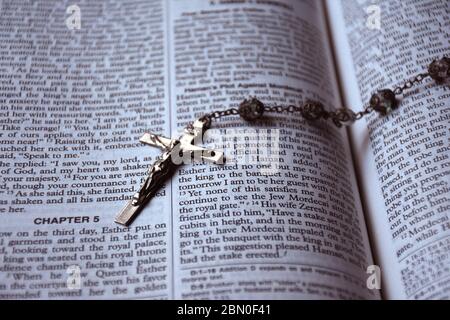 Crucifix avec perles rosaires qui s'ouvrent sur une bible. Banque D'Images