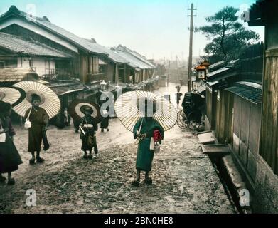 [ 1900s Japon - élèves de l'école élémentaire japonaise ] — élèves de l'école élémentaire avec parapluies en papier sur leur chemin ou retour de l'école pendant une journée de pluie. diapositive en verre vintage du xixe siècle. Banque D'Images