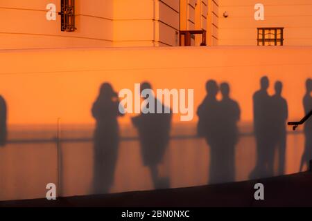 Les visiteurs jettent des ombres sur le mur de l'observatoire Griffith Park au coucher du soleil tout en observant la couleur de Los Angeles, Californie, États-Unis Banque D'Images