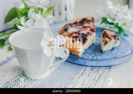 Tasse en porcelaine blanche avec thé vert et fleur de poire blanche fraîche et tarte aux baies maison avec baies sur un plat bleu en arrière-plan. Magnifique Banque D'Images