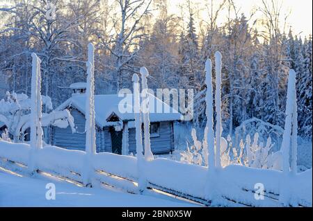 Une clôture enneigée devant une cabane en rondins, Boda kyrkby, Rättvik, Dalarna, Suède Banque D'Images