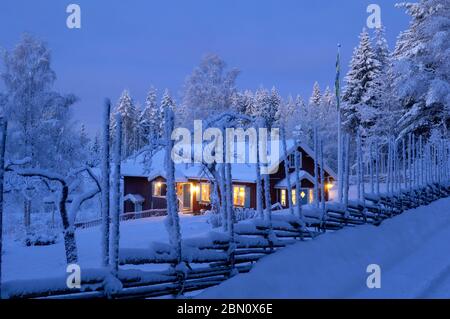 Une clôture enneigée devant une maison rouge traditionnelle de falu, Boda kyrkby, Rättvik, Dalarna Banque D'Images