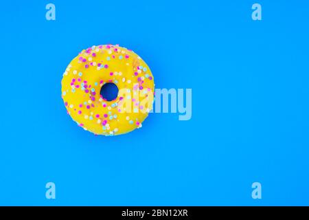 Beignet jaune délicieux isolé sur fond bleu. Banque D'Images