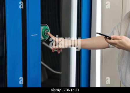 Femme index de main appuie sur le bouton pour ouvrir les portes dans la voiture de métro. Réglementation des transports publics, passager responsable Banque D'Images