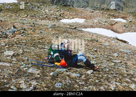 Jeune fille touriste alpiniste dans des vêtements spéciaux et sac à dos assis sur une surface de montagne et de repos après la conquête du sommet. Concept de l'outdo Banque D'Images