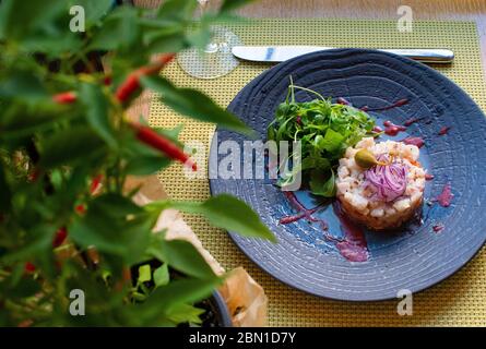 Tartre de poisson servi sur une assiette noire dans un cadre de restaurant Banque D'Images