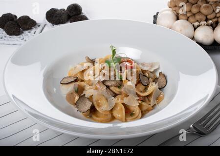 Pâtes d'orecchiette avec ceps, tomates cerises, gratin de ricotta, truffes fraîches et champignons sauvages. L'orecchiette est une pâte typique d'Apulia, une région o Banque D'Images