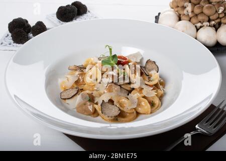 Pâtes d'orecchiette avec ceps, tomates cerises, gratin de ricotta, truffes fraîches et champignons sauvages. L'orecchiette est une pâte typique d'Apulia, une région o Banque D'Images