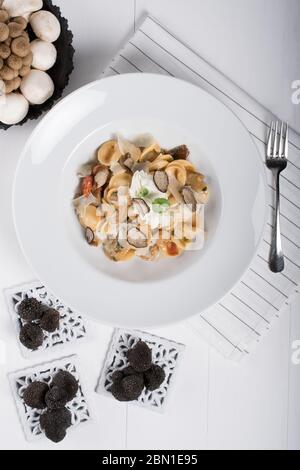 Pâtes d'orecchiette avec ceps, tomates cerises, gratin de ricotta, truffes fraîches et champignons sauvages. L'orecchiette est une pâte typique d'Apulia, une région o Banque D'Images