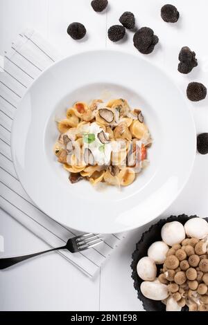 Pâtes d'orecchiette avec ceps, tomates cerises, gratin de ricotta, truffes fraîches et champignons sauvages. L'orecchiette est une pâte typique d'Apulia, une région o Banque D'Images