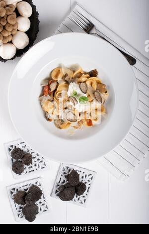 Pâtes d'orecchiette avec ceps, tomates cerises, gratin de ricotta, truffes fraîches et champignons sauvages. L'orecchiette est une pâte typique d'Apulia, une région o Banque D'Images