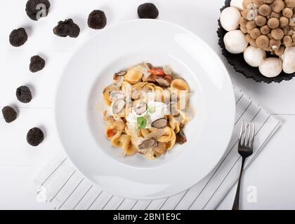 Pâtes d'orecchiette avec ceps, tomates cerises, gratin de ricotta, truffes fraîches et champignons sauvages. L'orecchiette est une pâte typique d'Apulia, une région o Banque D'Images