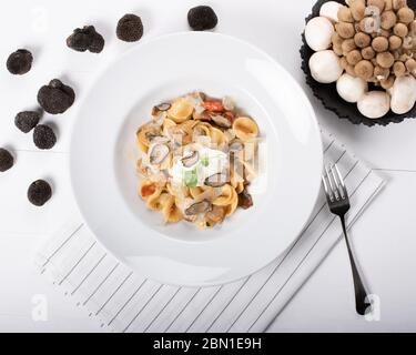 Pâtes d'orecchiette avec ceps, tomates cerises, gratin de ricotta, truffes fraîches et champignons sauvages. L'orecchiette est une pâte typique d'Apulia, une région o Banque D'Images