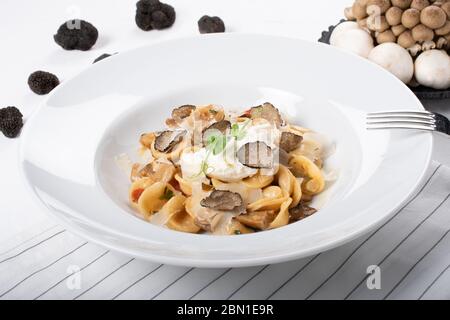 Pâtes d'orecchiette avec ceps, tomates cerises, gratin de ricotta, truffes fraîches et champignons sauvages. L'orecchiette est une pâte typique d'Apulia, une région o Banque D'Images