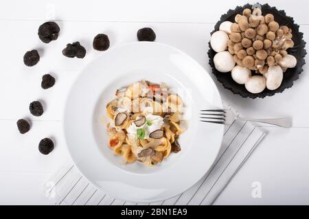 Pâtes d'orecchiette avec ceps, tomates cerises, gratin de ricotta, truffes fraîches et champignons sauvages. L'orecchiette est une pâte typique d'Apulia, une région o Banque D'Images