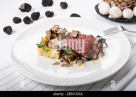 Filet de bœuf parfumé aux truffes, truffe locale, gratin de pommes de terre, champignons sauvages sautés, sauce au fromage Banque D'Images