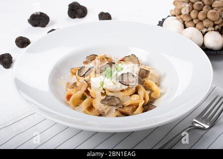 Pâtes d'orecchiette avec ceps, tomates cerises, gratin de ricotta, truffes fraîches et champignons sauvages. L'orecchiette est une pâte typique d'Apulia, une région o Banque D'Images